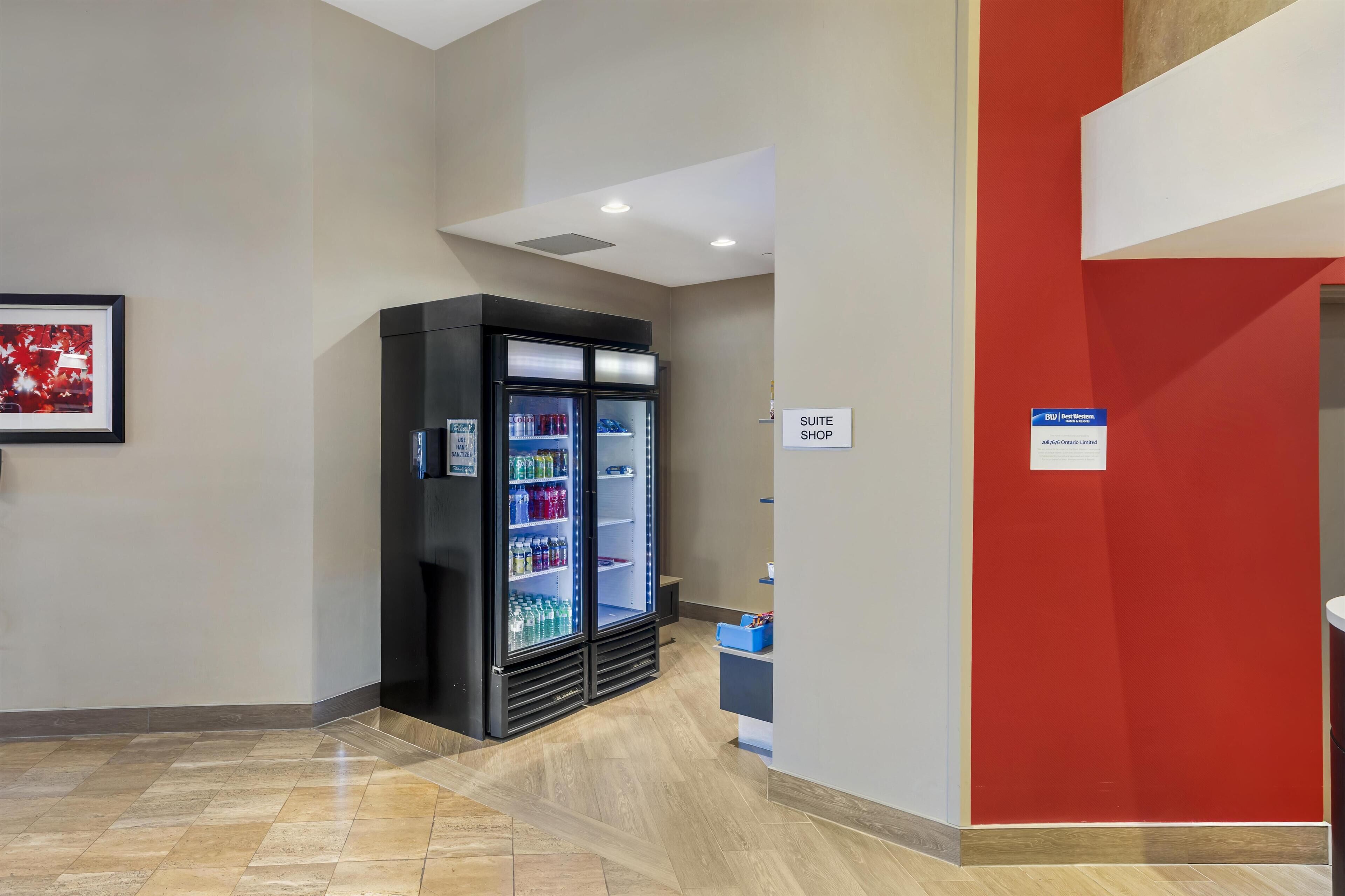 A hotel corridor with a refrigerated display case, a 'SUITE SHOP' sign, and a framed picture on the wall.