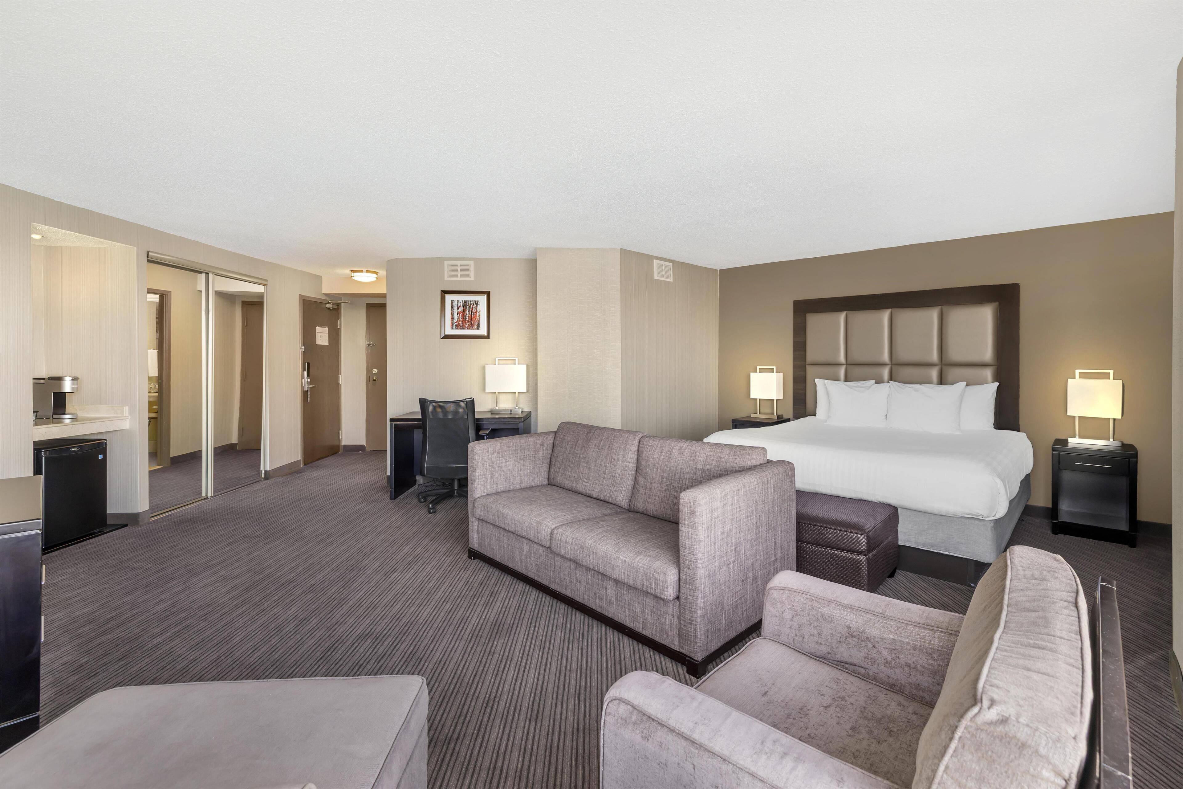 Quarto de hotel com uma cama, dois sofás, uma mesa de escritório e uma cadeira.