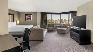 A hotel room with a bed, a desk, a TV, a sofa, and a view of the city. - Best Western Plus Waterfront Hotel (Windsor)