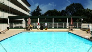 A swimming pool with a covered deck area, lounge chairs, and American flags.