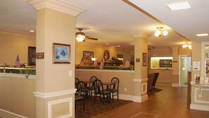A lobby with a reception desk, several chairs, and a tiled floor.