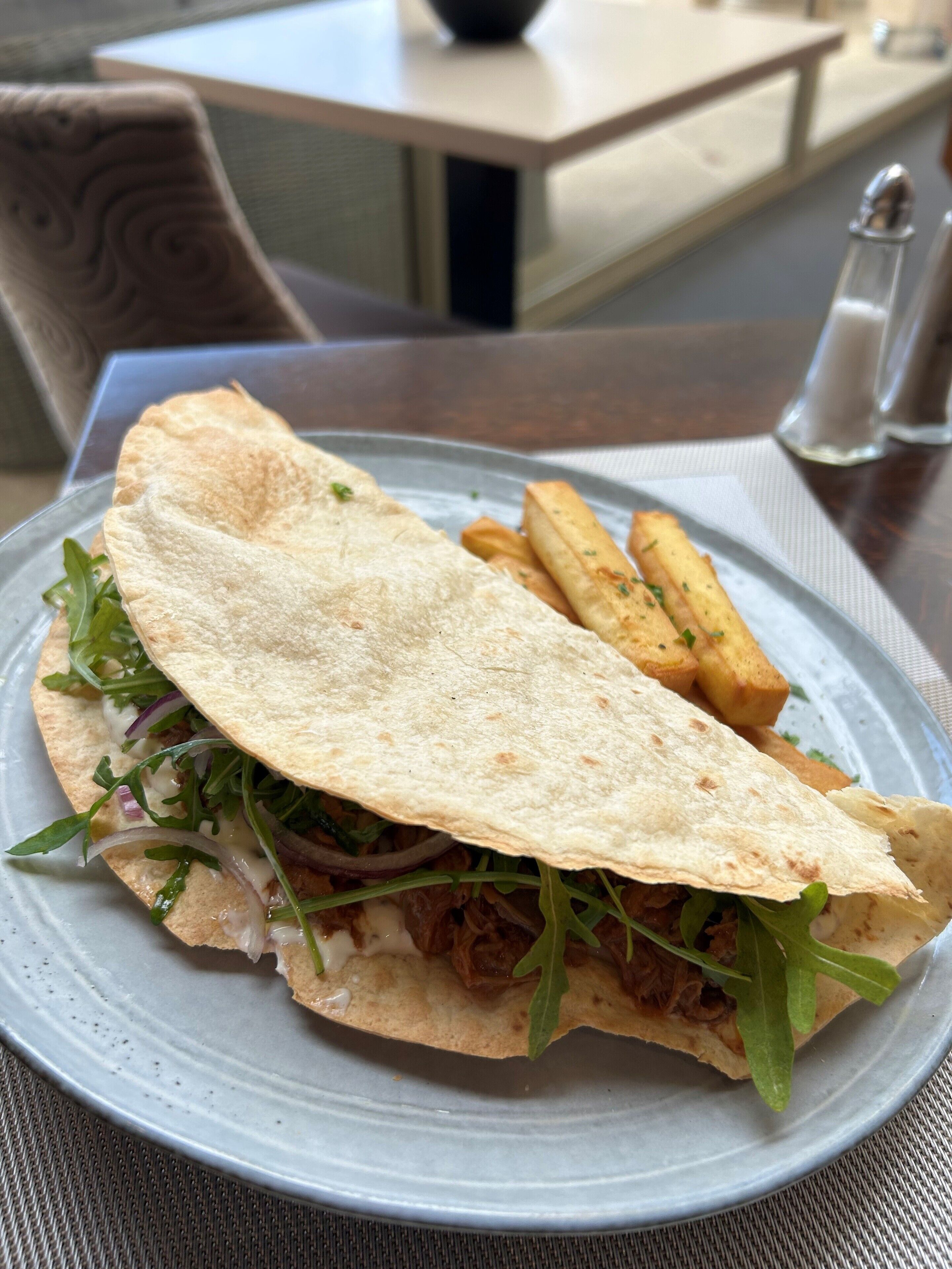 A plate with a sandwich and fries on a table.
