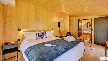 A wooden-paneled bedroom with a bed, bedside table, chair, and a mirror.