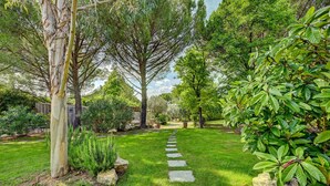 A garden with a stone pathway, lush greenery, and a variety of trees. - Best Western Sevan Parc Hotel (Pertuis)