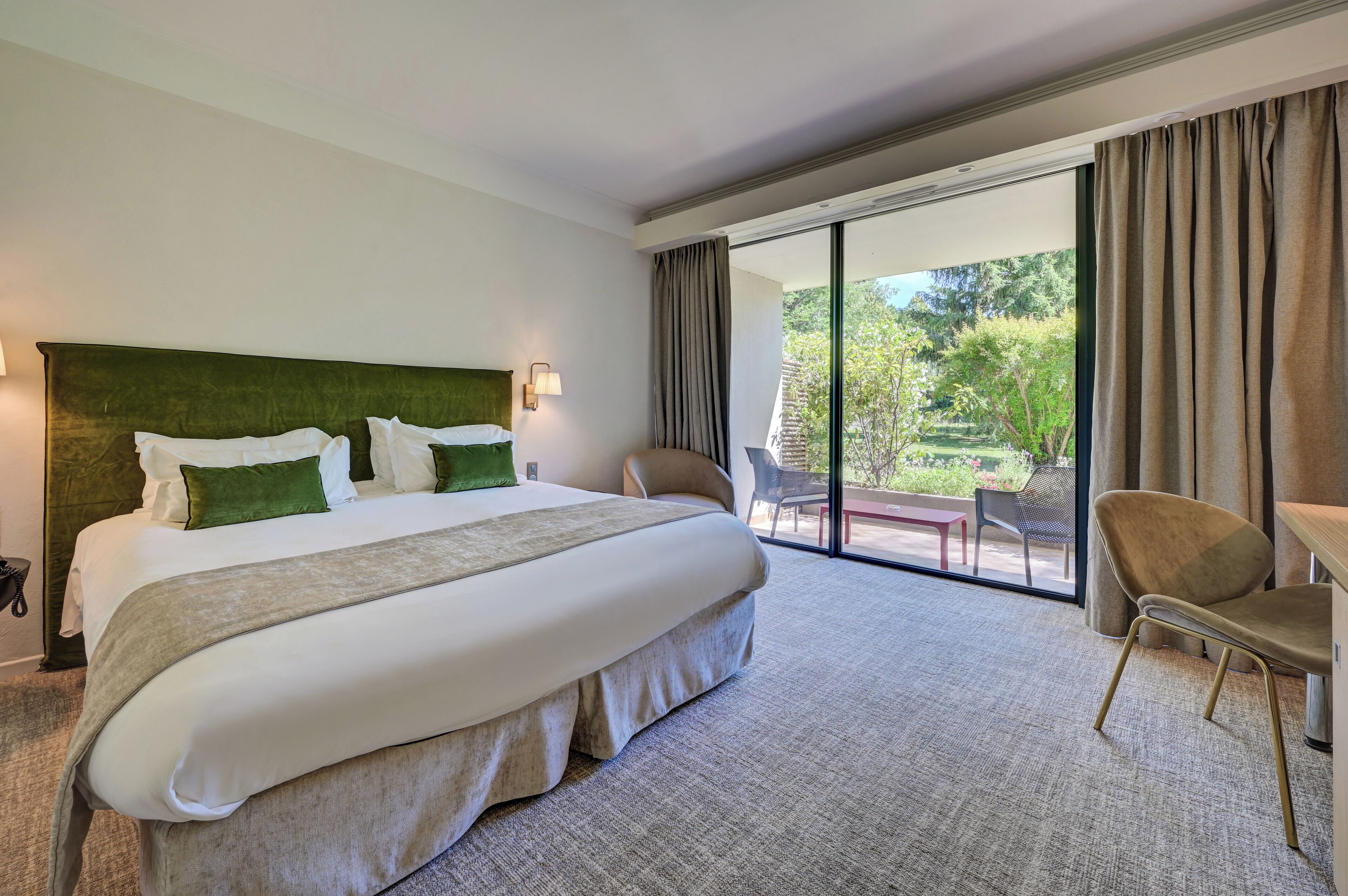 Habitación de hotel con una cama grande, un escritorio, una silla y vistas al exterior.