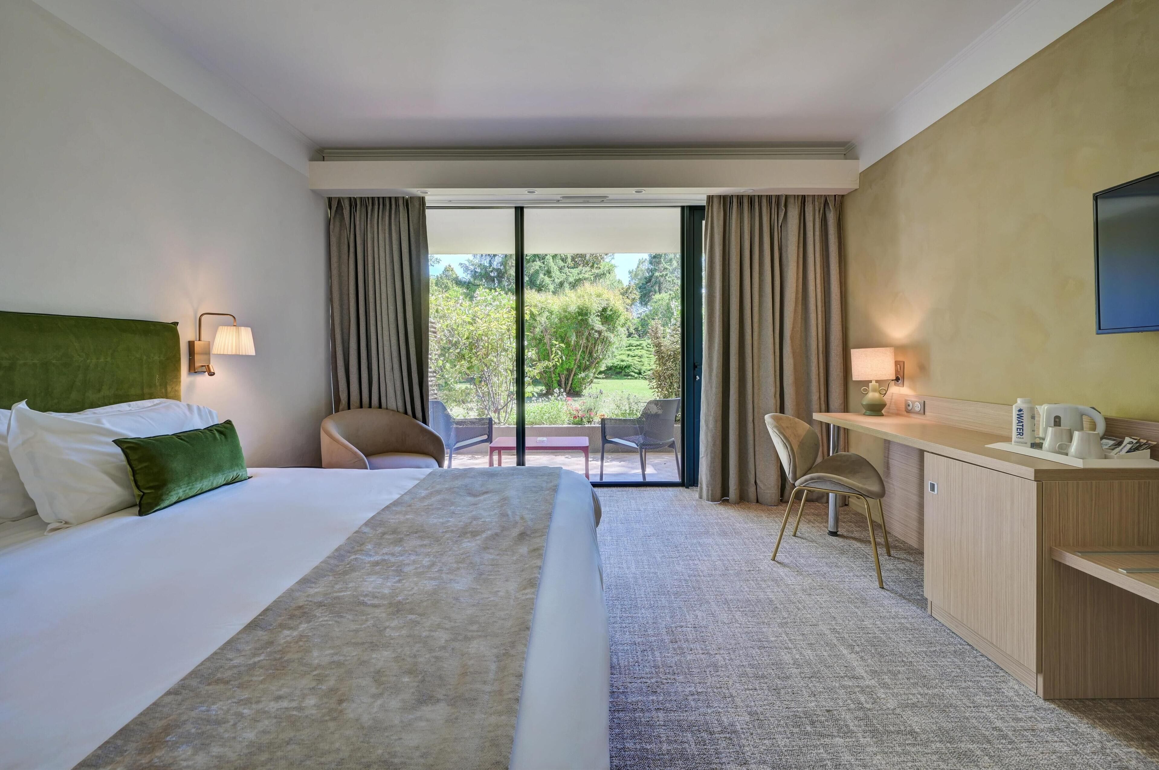 Une chambre d’hôtel avec un lit, un bureau, une chaise et une vue sur l’extérieur.