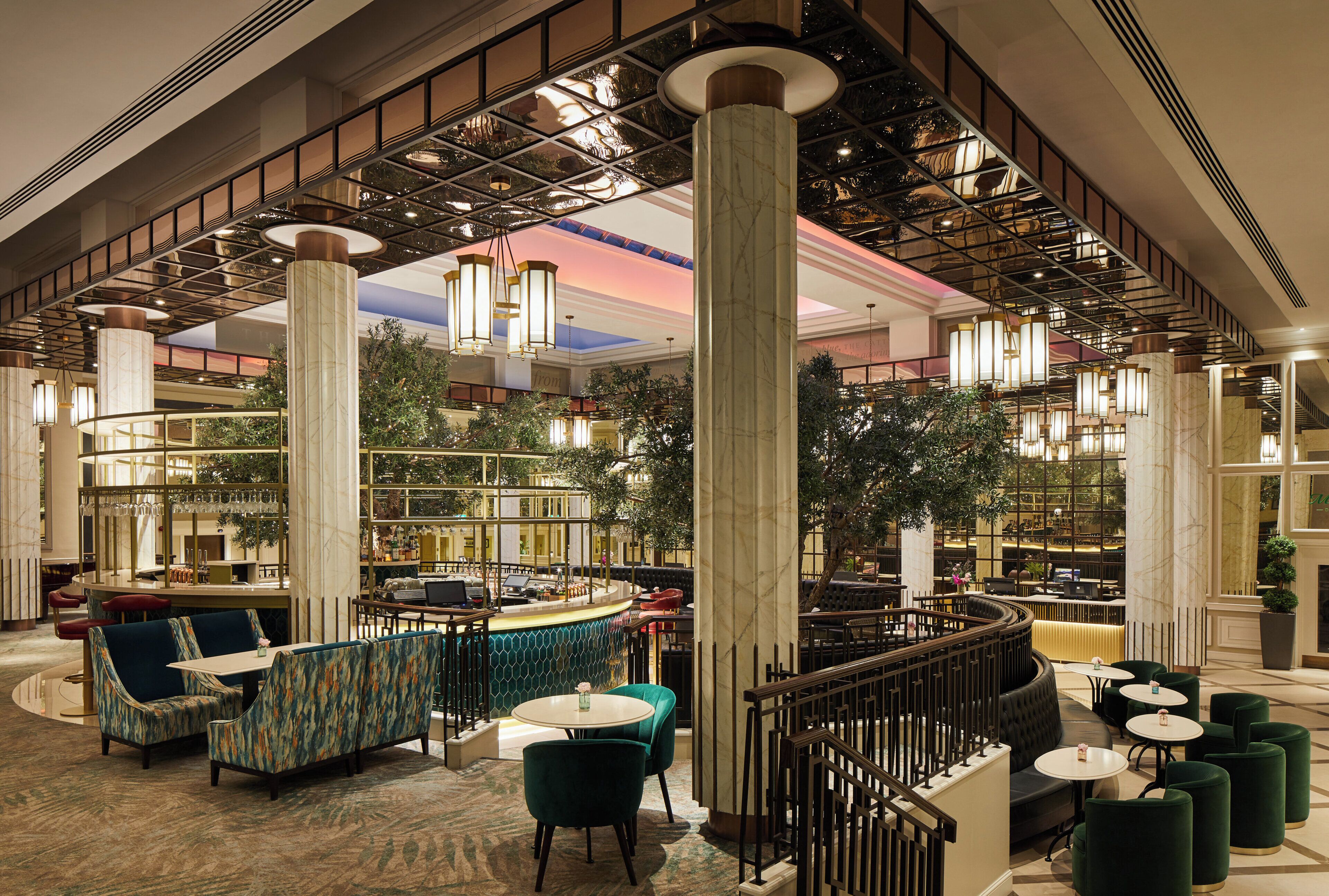 A spacious lobby with high ceilings, large columns, and a variety of seating arrangements including sofas and tables.