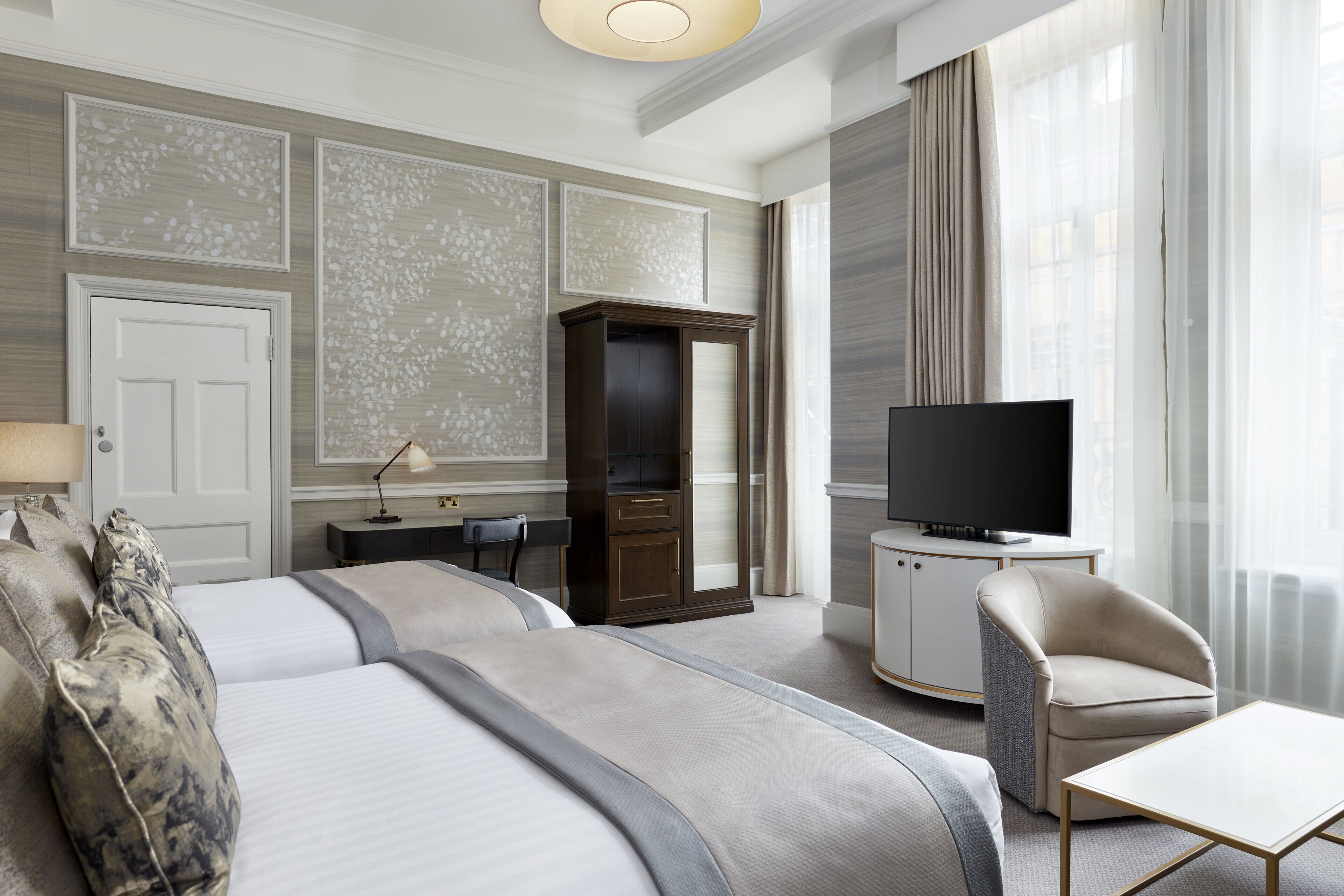 Habitación de hotel con dos camas, televisión, escritorio y una silla.