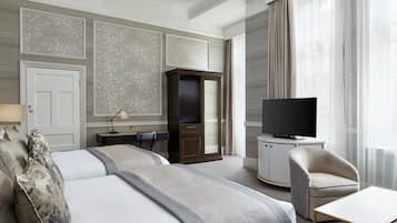 Habitación de hotel con dos camas, televisión, escritorio y una silla.