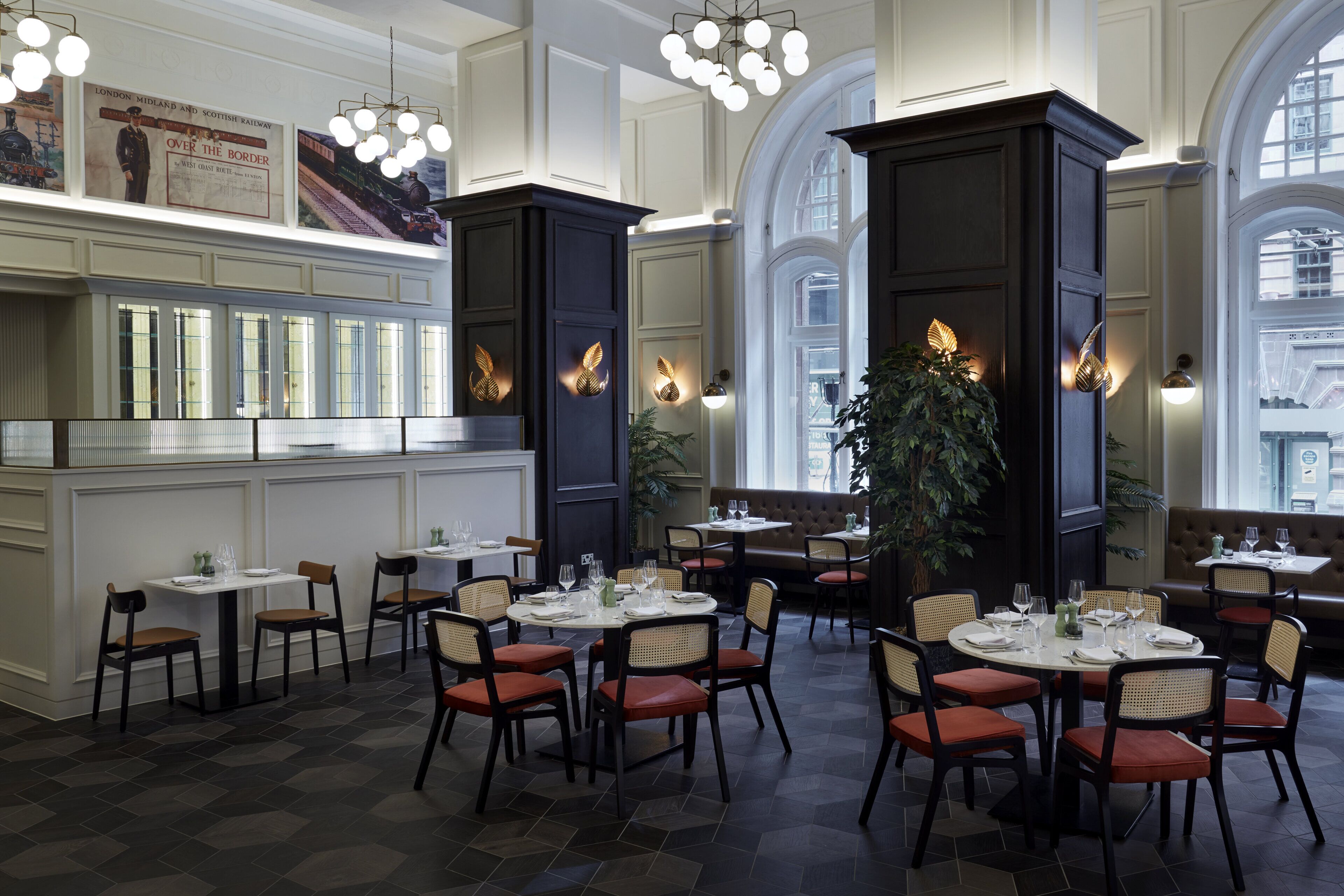 Un restaurante con techos altos, amplias ventanas y diferentes opciones de asientos, incluyendo mesas y cabinas.