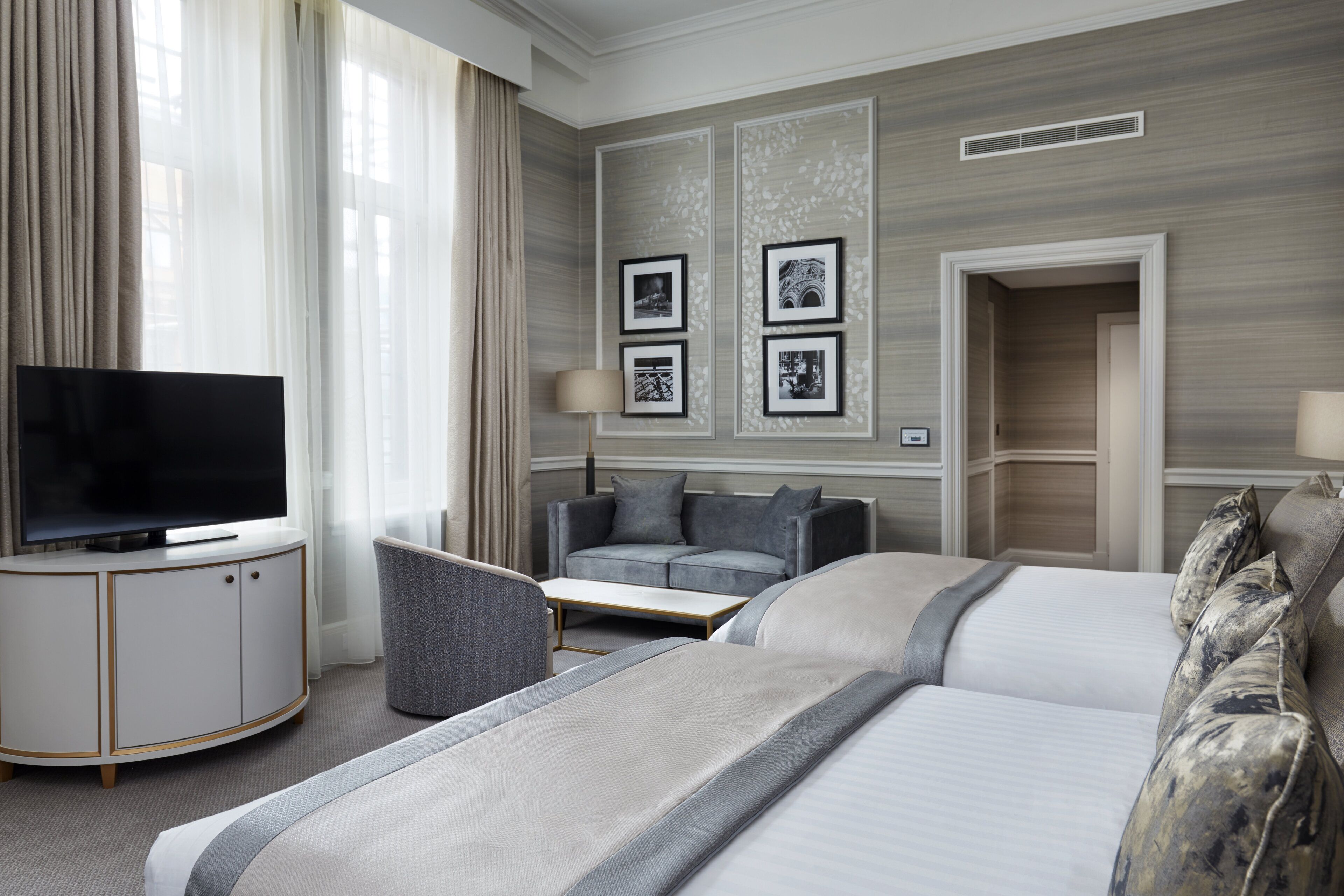 Et hotelværelse med en seng, en sofa, et fjernsyn og et skrivebord.