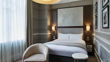 A hotel room with a large bed, two bedside tables, a chair, and a small side table.