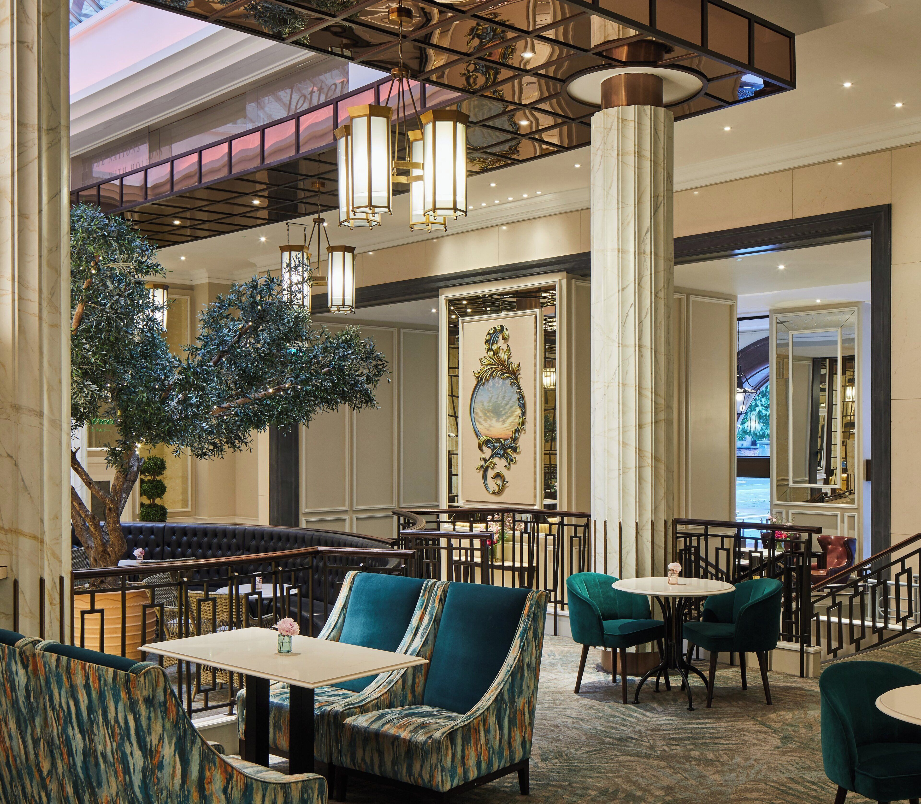 A spacious lobby with a large artificial tree, comfortable seating areas, and a grand staircase.