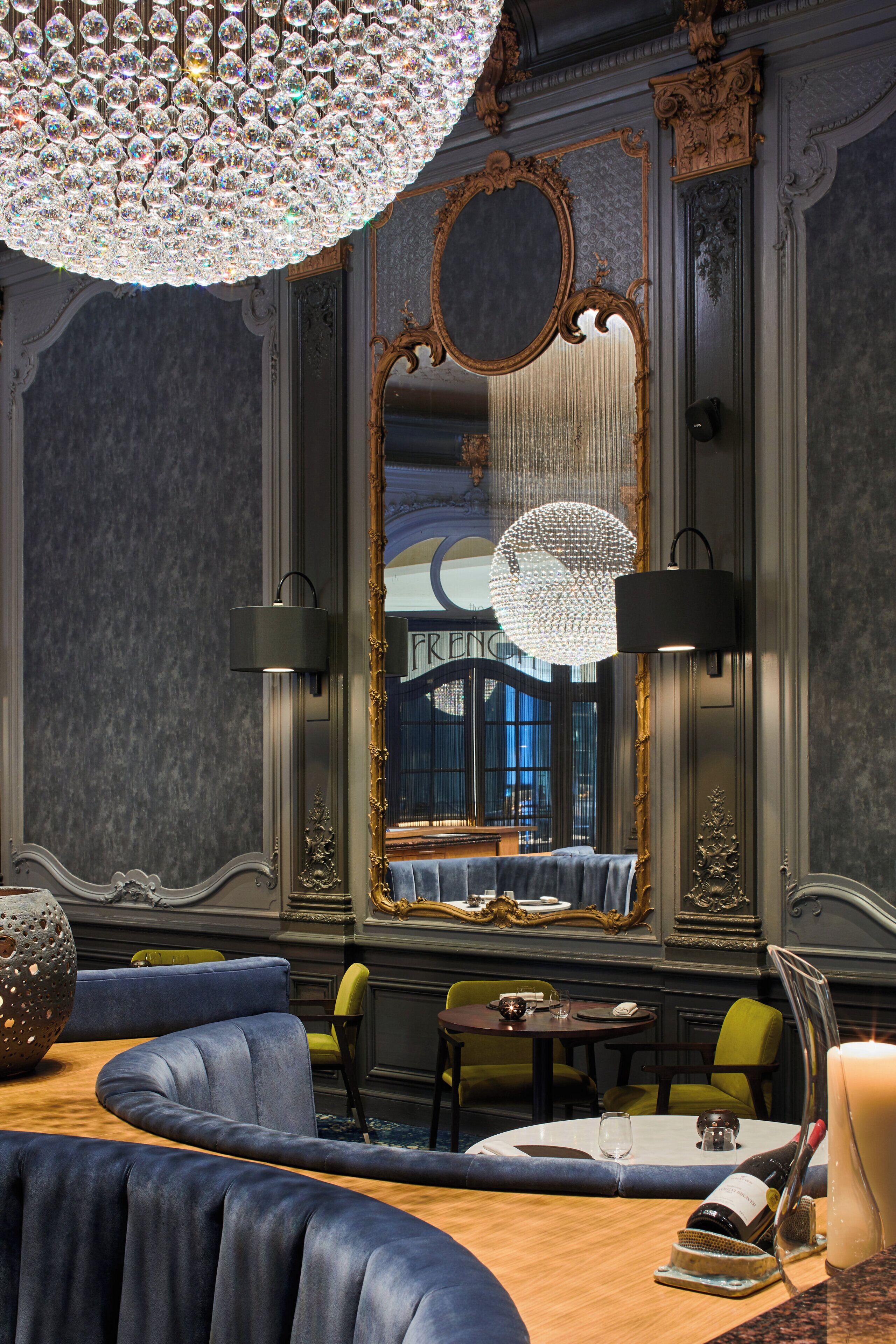 A luxurious room with a large mirror, elegant furniture, and a chandelier.
