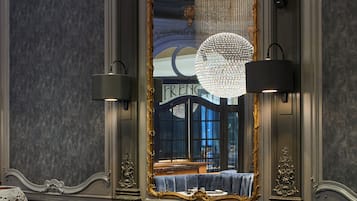 Una habitación lujosa con un espejo grande, muebles elegantes y una araña.