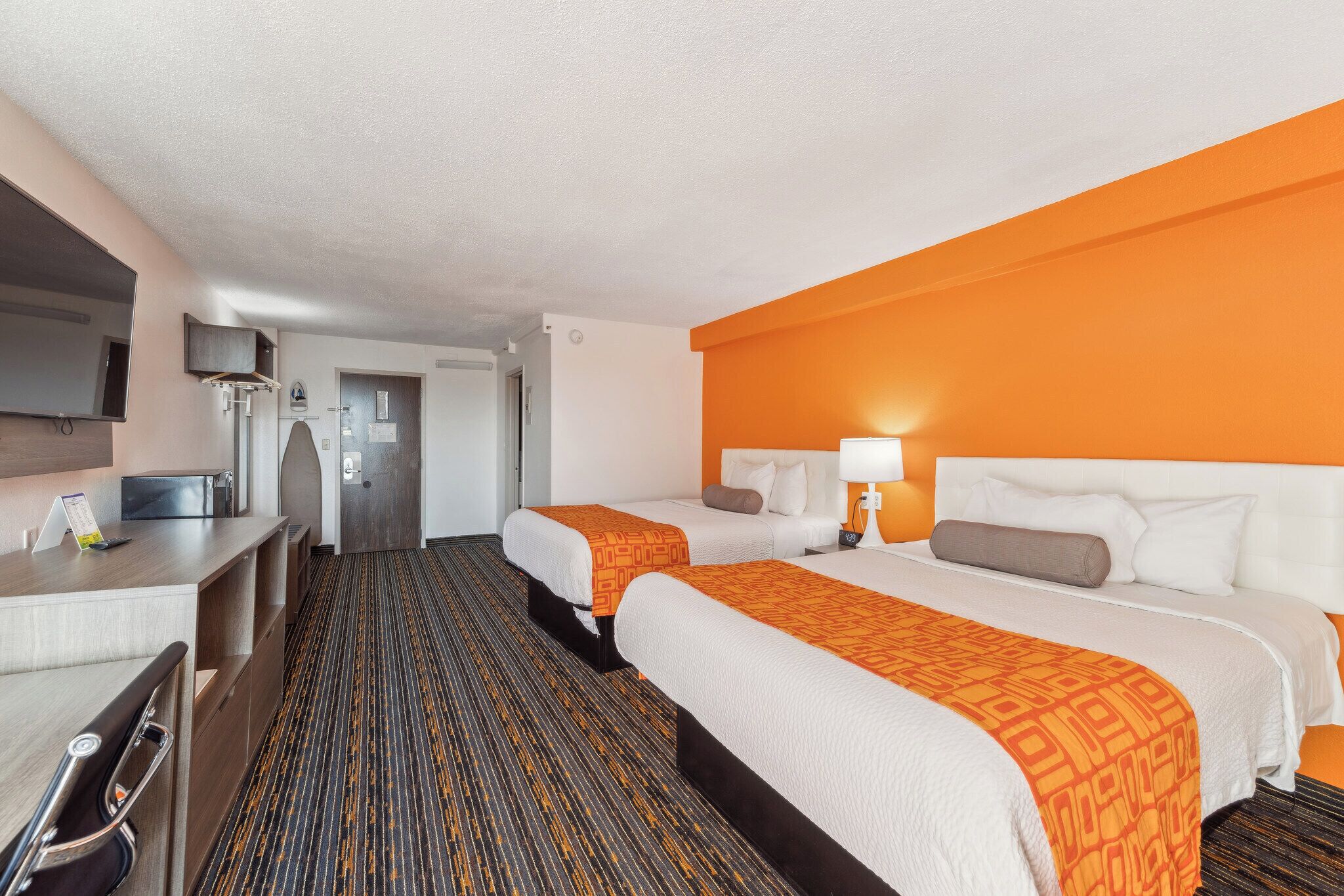 Ein Hotelzimmer mit zwei Betten, einem Schreibtisch, einem Fernseher und einem Badezimmer.