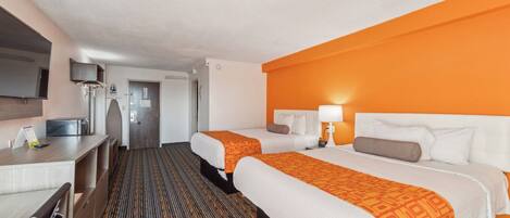 A hotel room with two beds, a desk, a TV, and a bathroom.