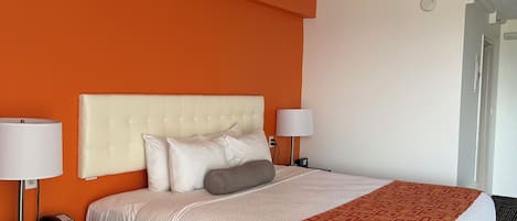 Habitación de hotel con una cama grande, dos mesitas de noche, un teléfono y una manta decorativa.