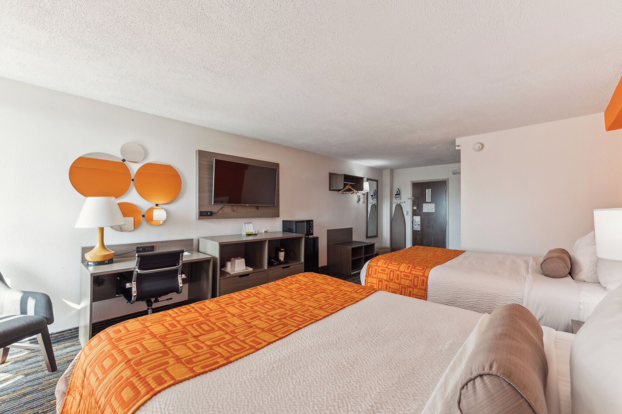 Ein Hotelzimmer mit zwei Betten, einem Schreibtisch, einem Stuhl, einem Fernseher und einem im Hintergrund sichtbaren Badezimmer.