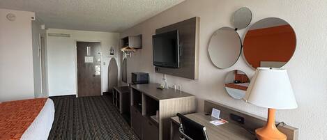 Ein Hotelzimmer mit Bett, Schreibtisch, Stuhl, Fernseher und Lampe.