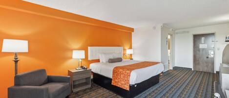 Une chambre d’hôtel avec un lit, une chaise, un bureau et une table de chevet.