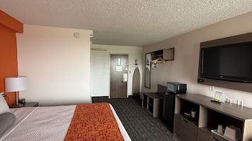Une chambre d’hôtel avec un grand lit, un bureau, un téléviseur à écran plat et un dressing.