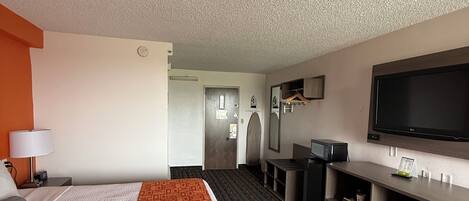 Una habitación de hotel con una cama grande, un escritorio, un televisor de pantalla plana y un vestidor.