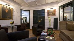 Un moderno vestíbulo de hotel con un sofá, sillones, una mesa de centro y obras de arte enmarcadas en las paredes.