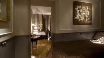 A hotel room with a large bed, a nightstand, a lamp, and a framed artwork on the wall.
