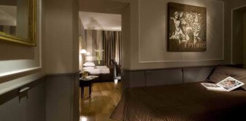 A hotel room with a large bed, a nightstand, a lamp, and a framed artwork on the wall.