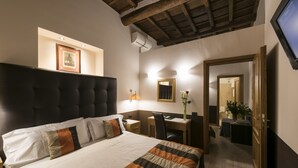 Habitación de hotel con una cama grande, un escritorio, una silla, un espejo y un televisor.