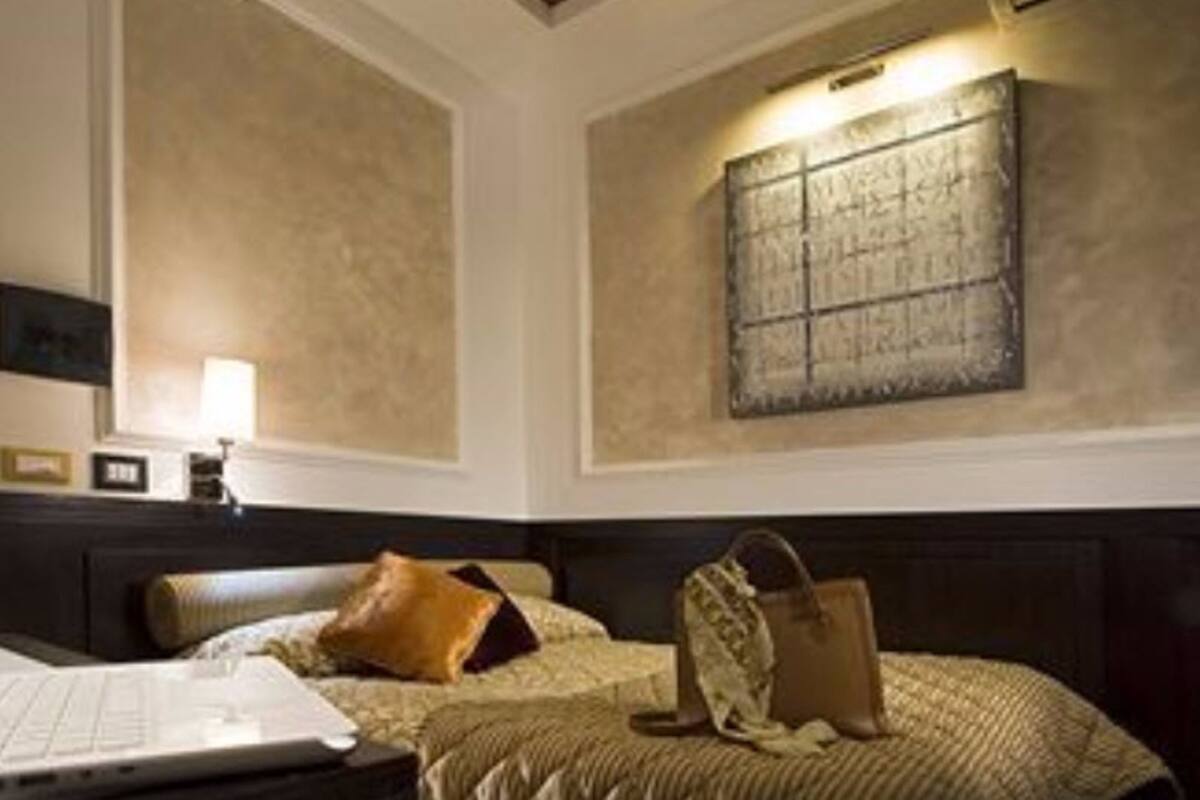 A hotel room with a bed, a desk, a lamp, and a wall-mounted artwork.