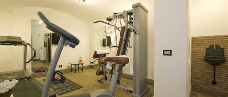 Un gimnasio de hotel con equipo de ejercicio, una cinta de correr y un espejo.