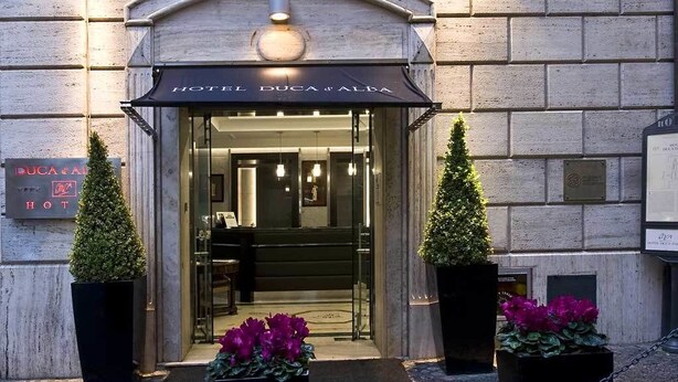 Entrada de un hotel con un cartel que dice 'HOTEL DUCA & ALBA'.