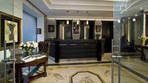 Un área de recepción con un mostrador negro, una división de vidrio y un trofeo enmarcado en la pared.