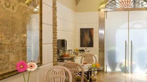 Un comedor con techo alto, arcos de piedra y un cuadro grande en la pared.
