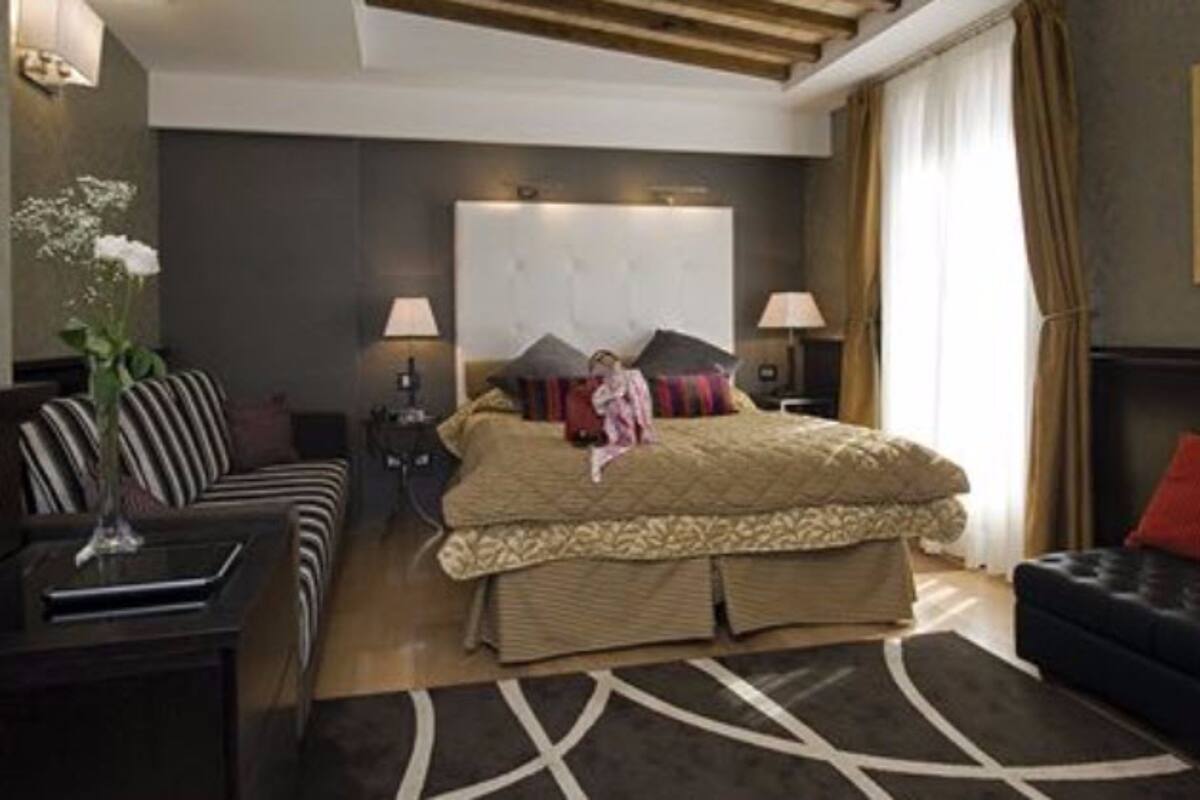 A modern bedroom with a large bed, two bedside tables, a sofa, and a decorative wall piece.