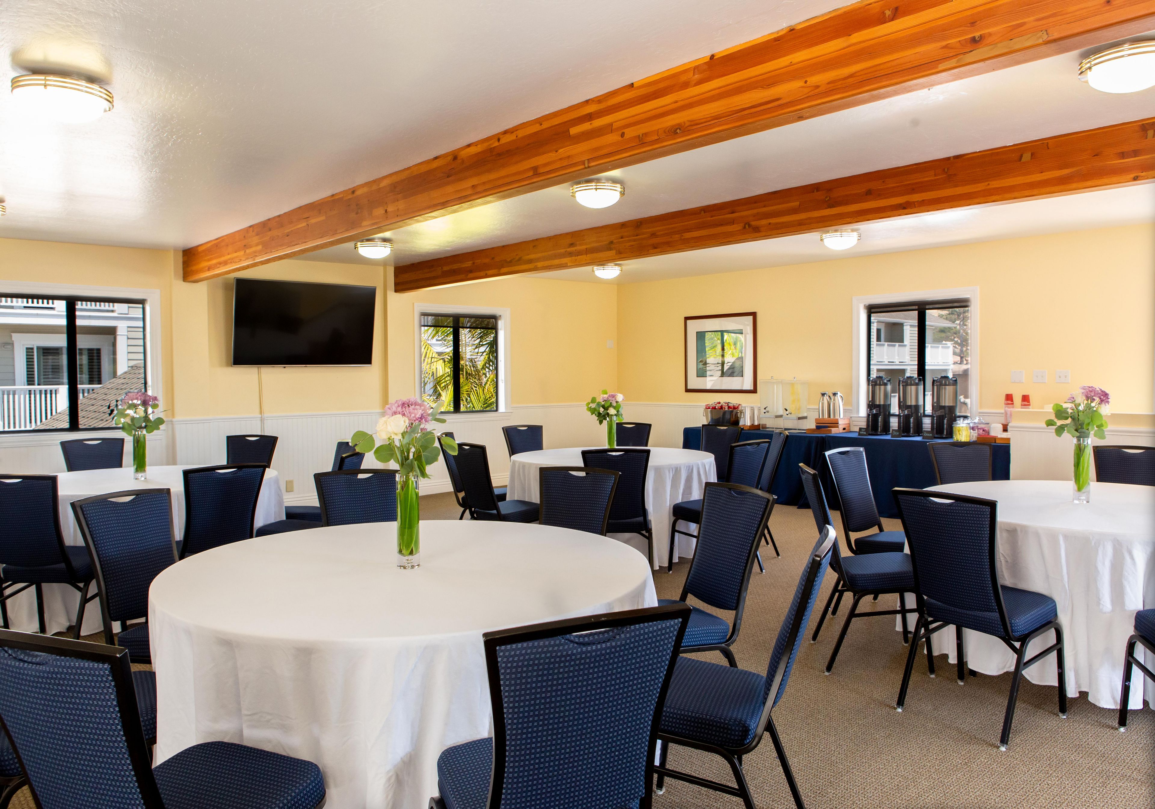 A conference room with round tables, blue chairs, and white tablecloths.