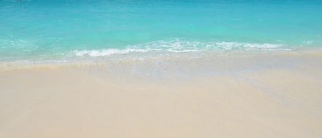 A beach with clear turquoise water and a sandy shore.
