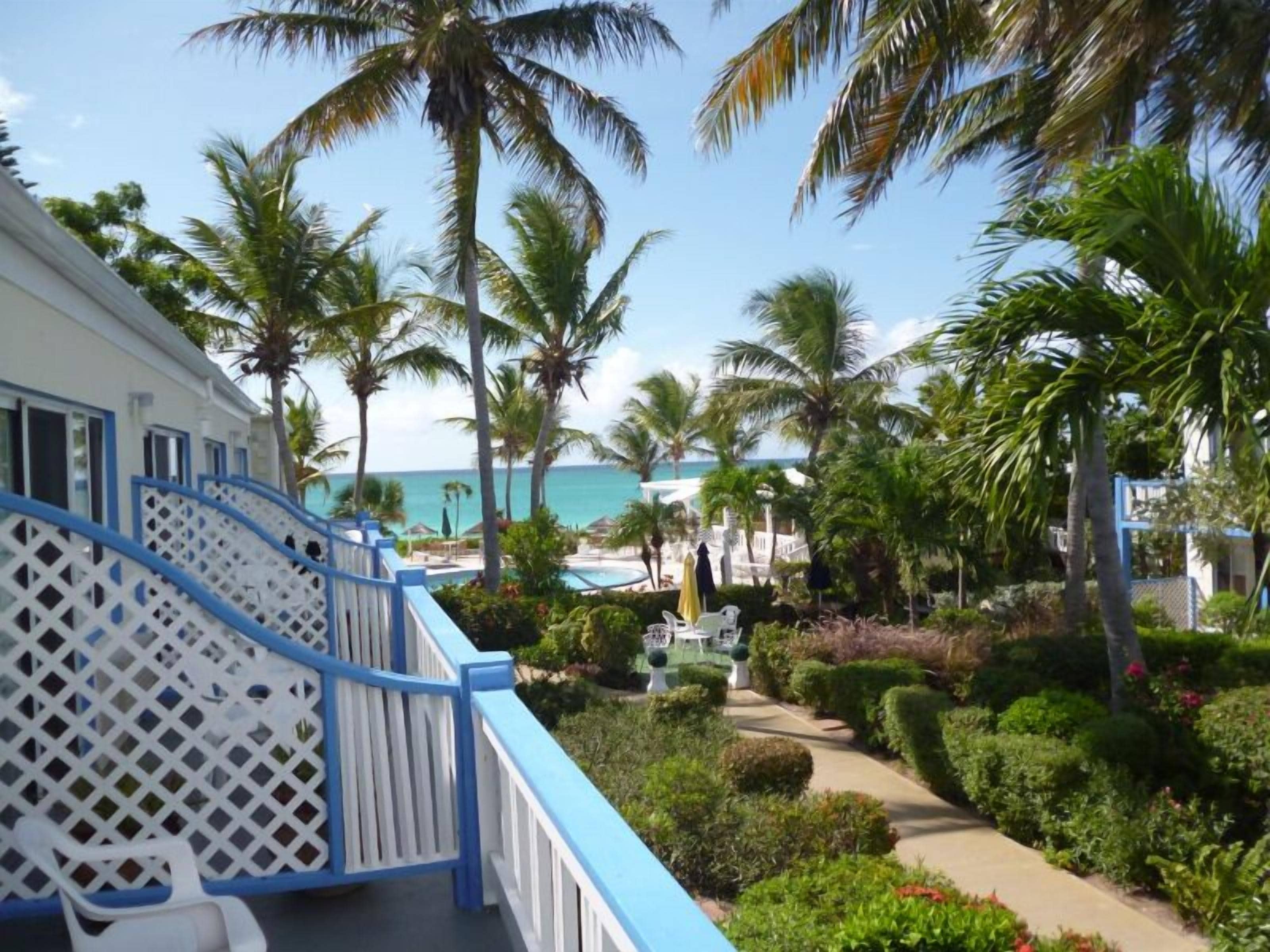 Un resort con piscina, palmeras y vista al océano.