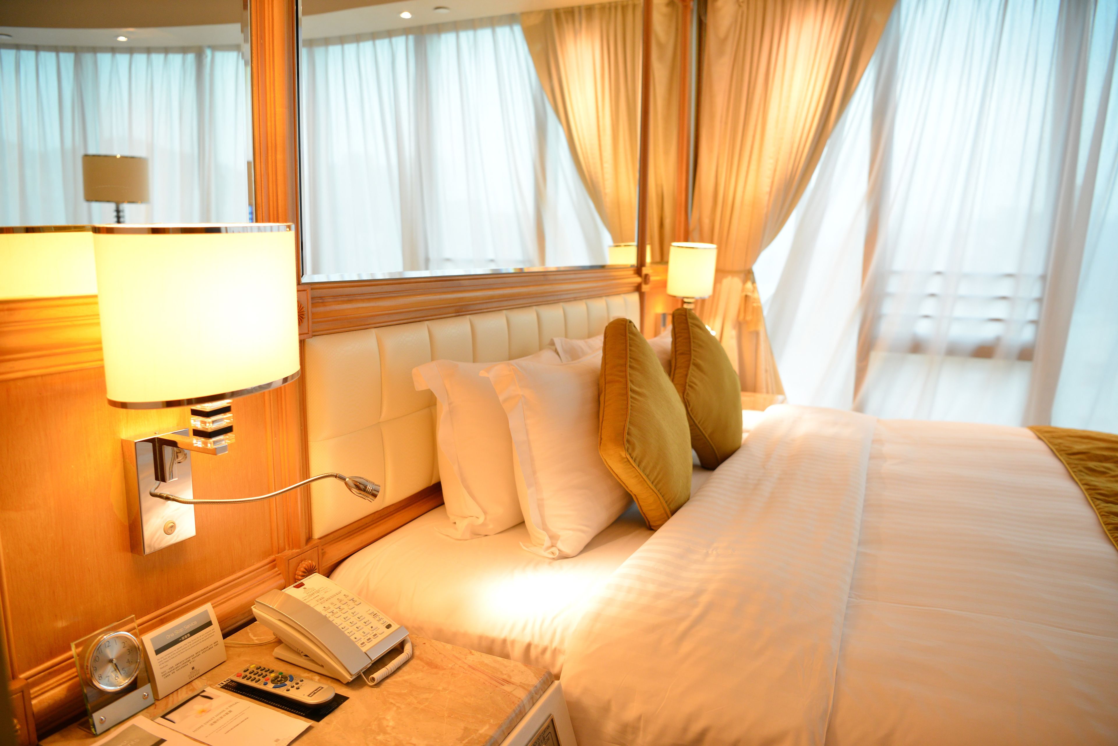 A hotel room with a bed, bedside lamps, a telephone, and a clock.