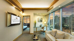 A hotel room with a city view, a glass desk, a sofa, and a coffee table. - Regal Hongkong Hotel (Hong Kong)