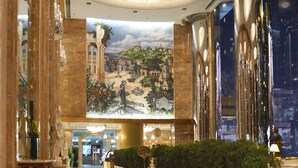 A spacious lobby with a high ceiling, ornate chandeliers, a large mural, and a reflective marble floor. - Regal Hongkong Hotel (Hong Kong)