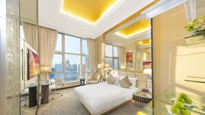 A hotel room with a large bed, a glass coffee table with apples, a desk with a laptop, and a view of the city. - Regal Hongkong Hotel (Hong Kong)