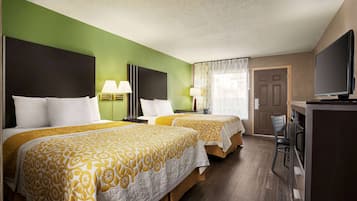 A hotel room with two beds, a television, a desk with a chair, and a door.