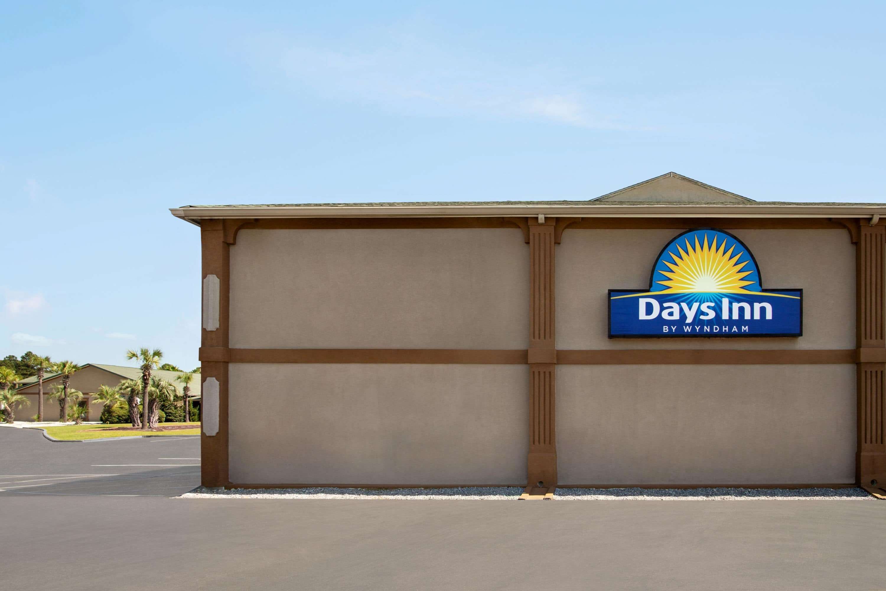 A Days Inn sign on a building facade with a clear sky in the background.