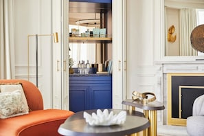 A modern living room with a blue kitchen area, a fireplace, and a round table with a decorative item.
