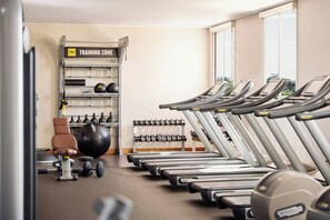 Un gimnasio con cintas de correr, pelotas de ejercicio y mancuernas.