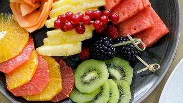 Una bandeja de frutas con diversas frutas cortadas, incluyendo naranjas, kiwi, sandía y frutos rojos.