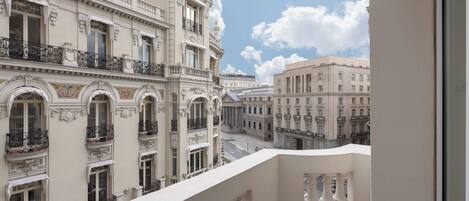 A view from a balcony overlooking a street with classical architecture, including ornate balconies and detailed facades.